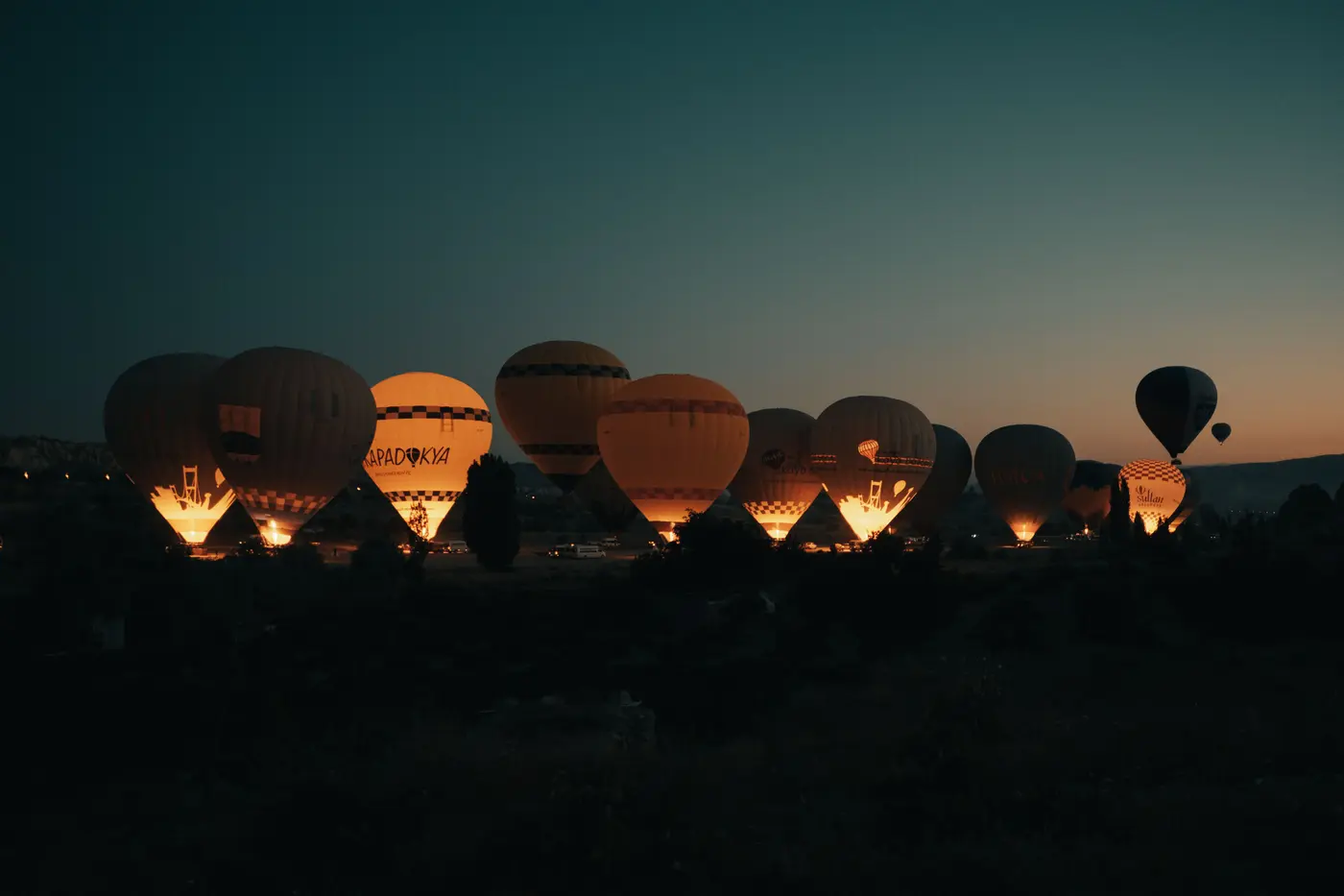 Hot air balloons lit by their burners before dawn