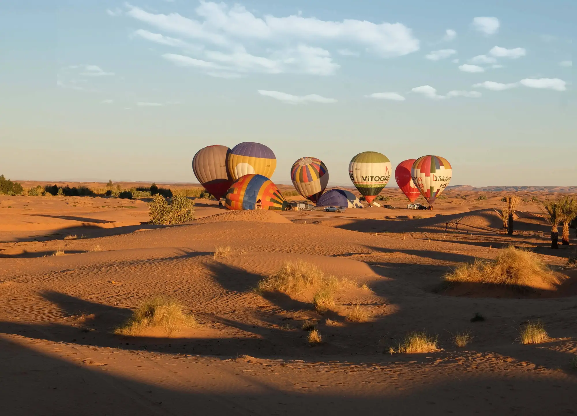 Globos aerostáticos posados en un paisaje desértico al amanecer